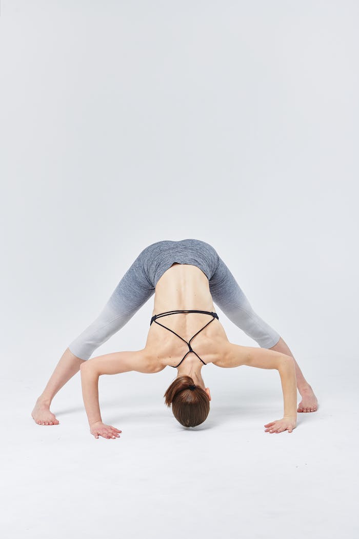 Woman practicing advanced yoga pose indoors showcasing flexibility and strength.